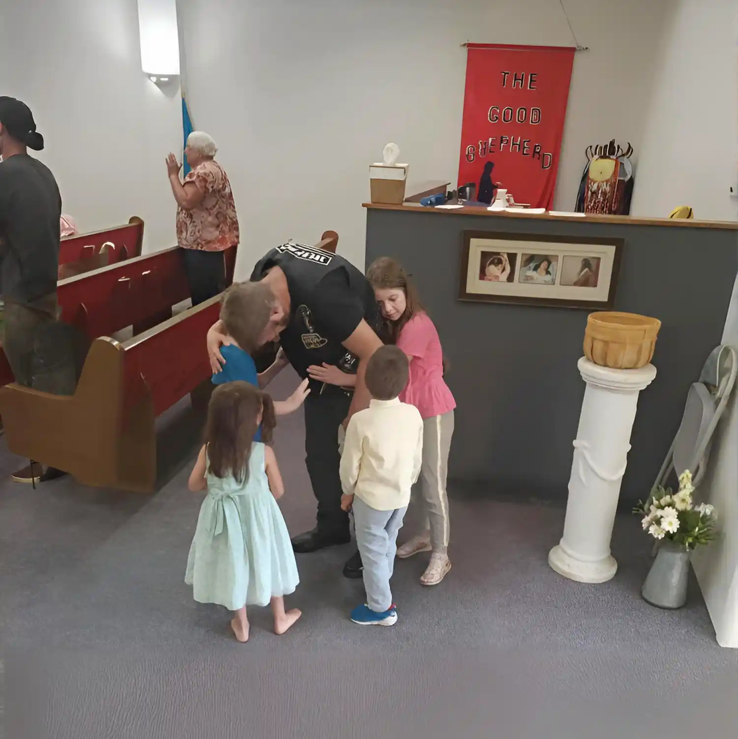 Pastor Troy praying with a family including children in church sanctuary